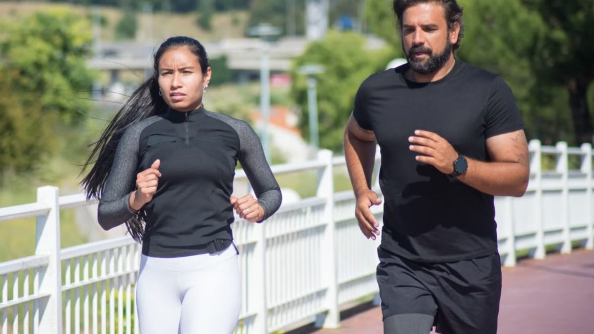 Active couple jogging outdoors on a sunny day, promoting fitness and healthy lifestyle.